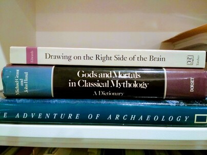 Three books lying horizontally on a white shelf, The Adventures of Archaeology, Gods and Mortal in Classical Mythology, Drawing on the Right Side of the Brain