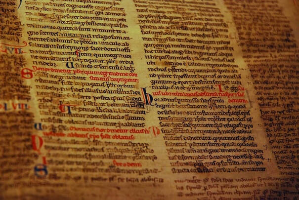 Folio of medieval Latin manuscript with headings written in red ink